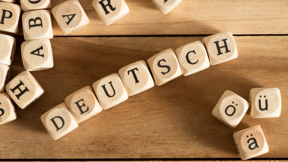 Buchstabenwürfel aus Holz liegen in einer Reihe und zeigen das Wort "deutsch"